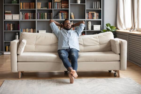 Serene,Relaxed,Barefoot,Young,African,Man,Resting,On,Comfortable,Couch