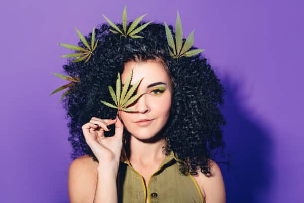 Mixed,Race,Woman,With,Afro curls,Holding,Hemp,Leaf.,The,Concept