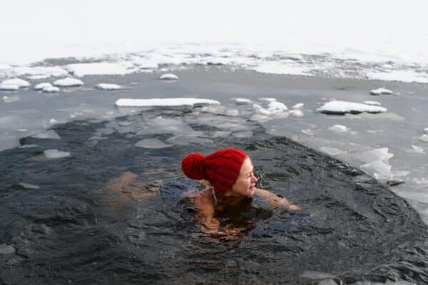Active,Senior,Woman,Swimming,In,Water,Hole,In,Frozen,Lake