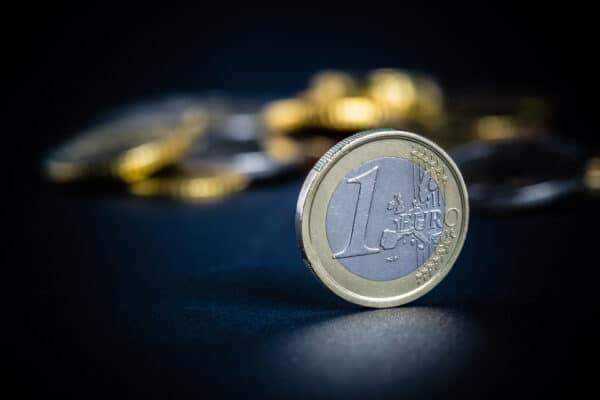 One,Euro,Coin,On,Black,Background,,With,Many,Coins,Blurred