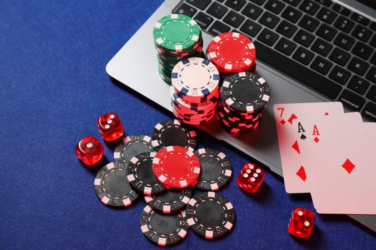 Poker,Chips,,Laptop,,Playing,Cards,And,Dices,On,Blue,Table,