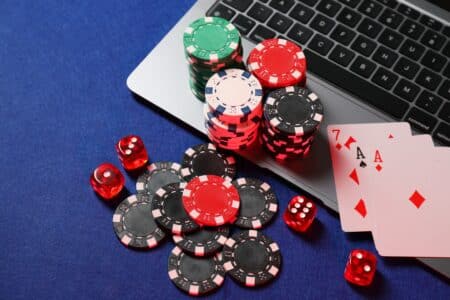 Poker,Chips,,Laptop,,Playing,Cards,And,Dices,On,Blue,Table,