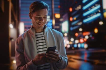 Portrait,Of,Man,Using,Smartphone,Walking,Through,Night,City,Street
