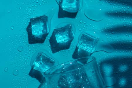 fresh ice cubes and glass on blue surface utc