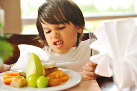 displeased young child with plate of food utc