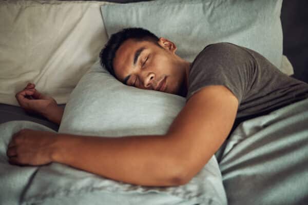 man sleeping peacefully in soft bed at home utc
