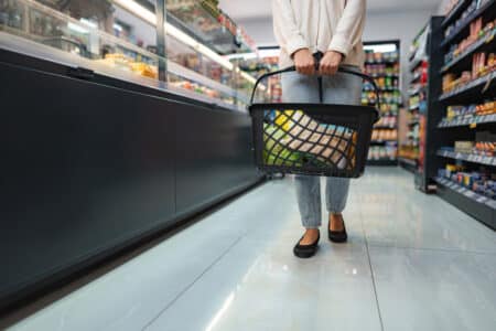 woman carrying shopping basket walking in supermar utc