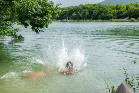 happy children swim in the lake in the summer utc